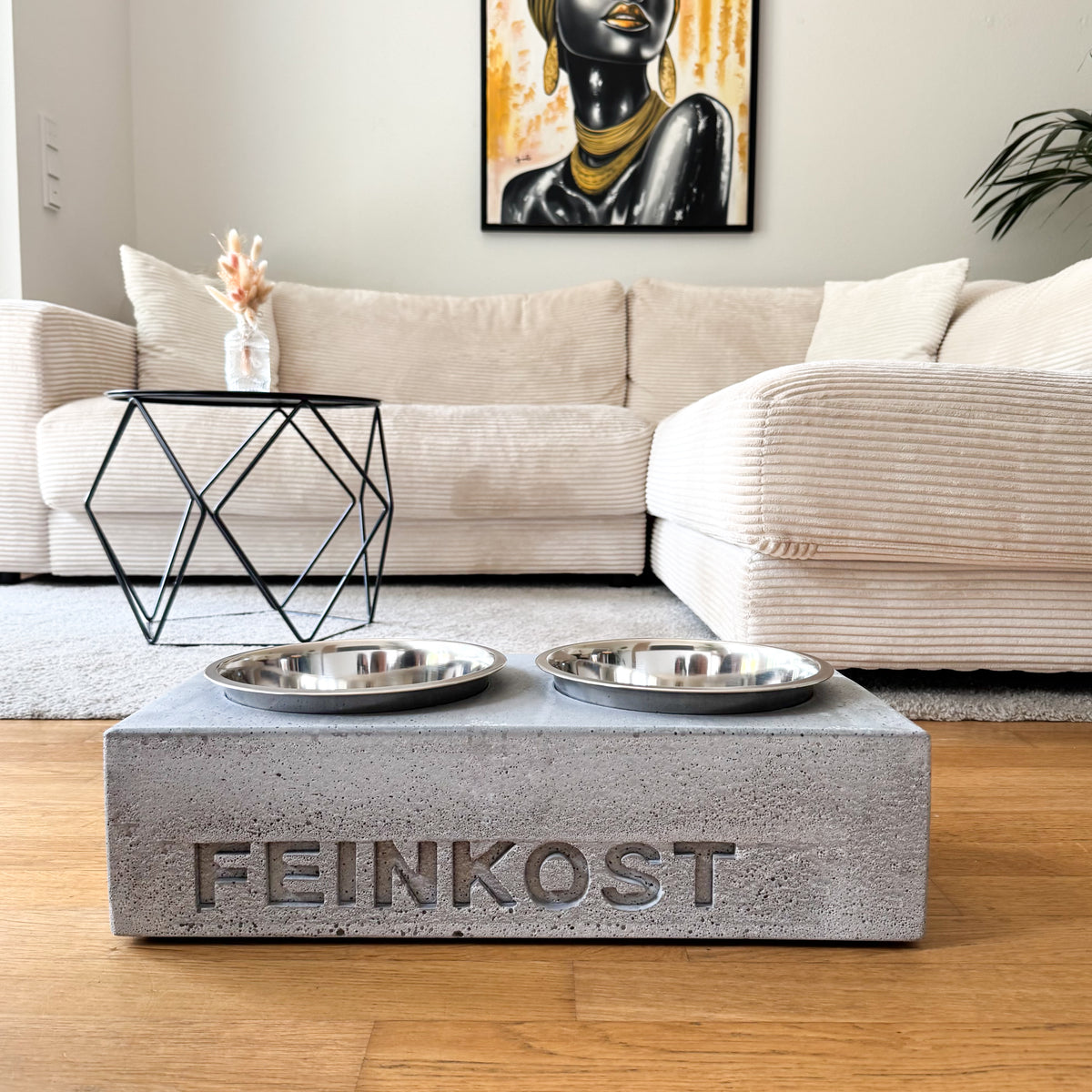 Napfhalter aus grauem Beton mit personalisiertem Namen und zwei Edelstahlnäpfen, frontal im Wohnraum